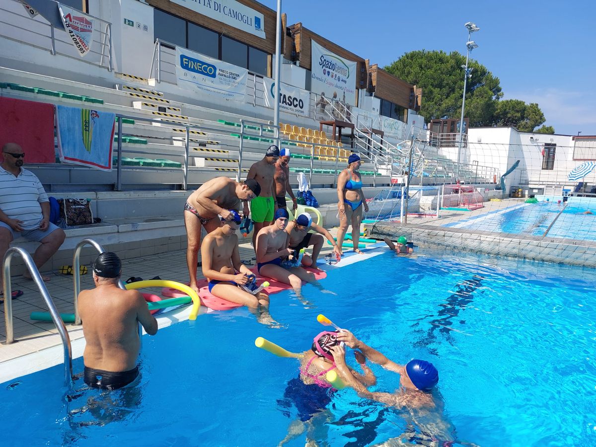 foto della preparazione ripresa da bordo vasca lateralmente, pochi allievi e istruttori in piscina ancora altri seduti sul bordo