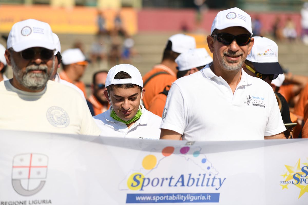 primo piano di persone del Centro che reggono lo striscione dello SportAbility in maglia e cappellino bianchi