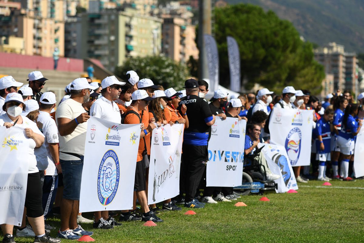 persone varie che reggono propri striscioni delle rispettive associazioni allo SportAbility sul prato
